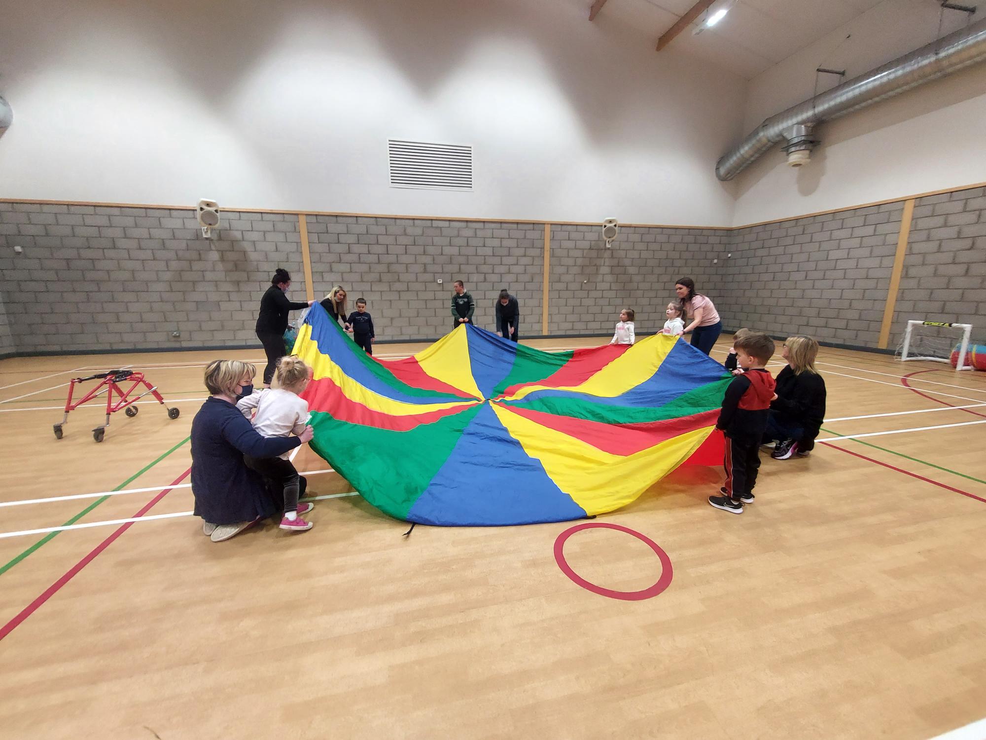 Pre-school children with disabilities and their parents and carers playing parachute games.